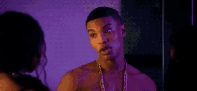 a woman with braids is standing in a dark room with purple lights behind her