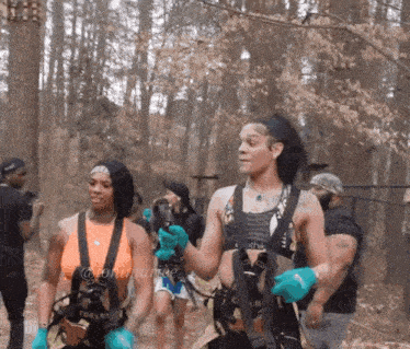 a group of women are walking through the woods and one of them is wearing a harness that says reebok on it
