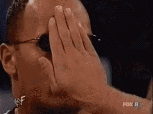 a man in sunglasses is covering his face with his hands .