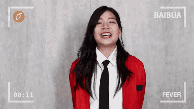 a woman in a red jacket and black tie is smiling in front of a camera that says baibua fever