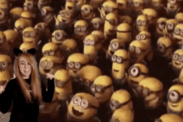 a woman is standing in front of a crowd of minions from the movie despicable me .