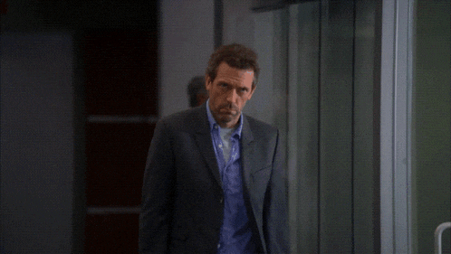 a man in a suit stands in front of a glass wall