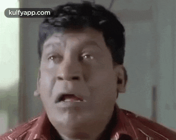 a man in a red shirt is making a funny face with his mouth open .