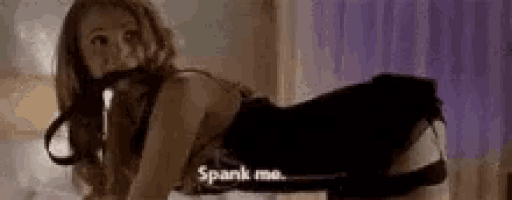 a woman in a corset is kneeling on a bed with a leash around her neck and says `` spank me '' .
