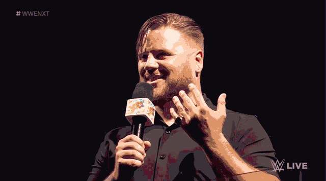a man holding a microphone in front of a sign that says wwe live