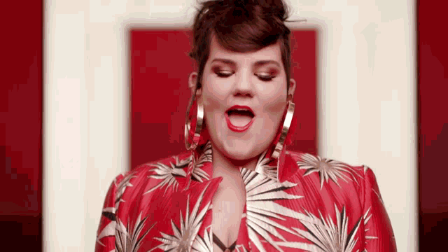 a woman wearing a red and white jacket and hoop earrings