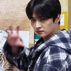 a young man in a plaid hoodie is waving his hand