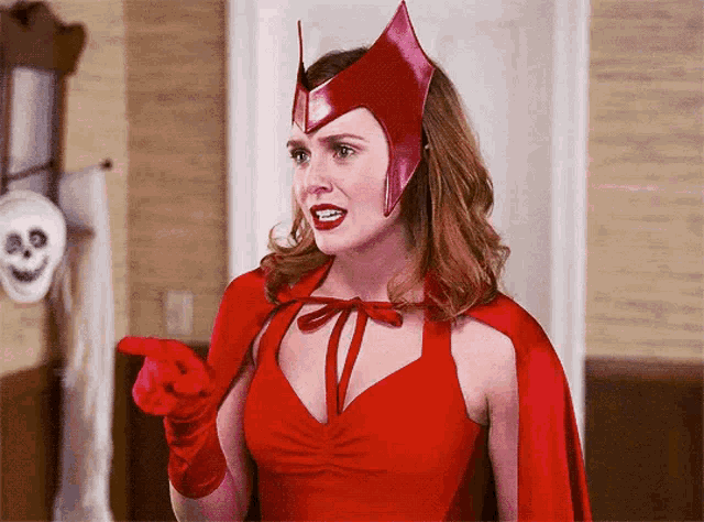 a woman in a red superhero costume is pointing at something .