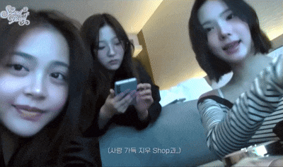 three girls are posing for a picture and one of them is holding a phone
