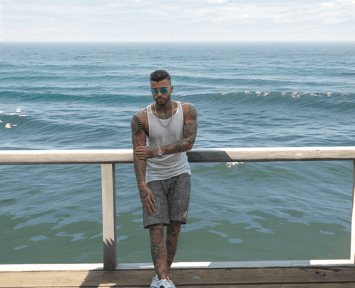 a man leaning against a railing looking out over the ocean