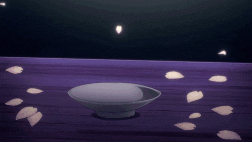a white bowl sits on a purple surface with petals falling on it