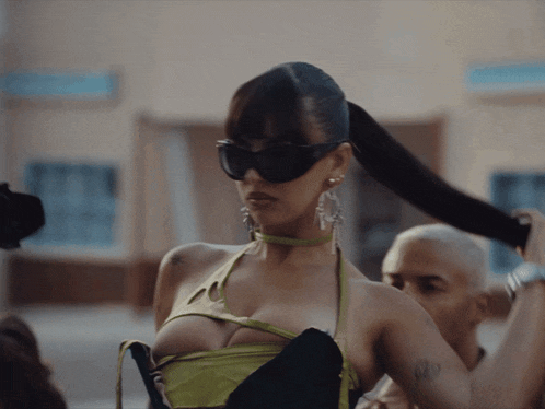 a woman wearing sunglasses and a green top has a tattoo on her arm that says 679