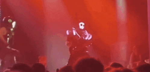 a man in a gas mask is dancing on a stage in front of a crowd at a concert .