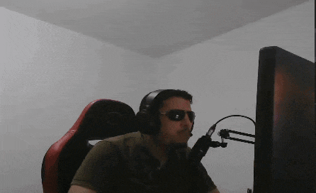 a man wearing headphones and sunglasses sits in front of a monitor