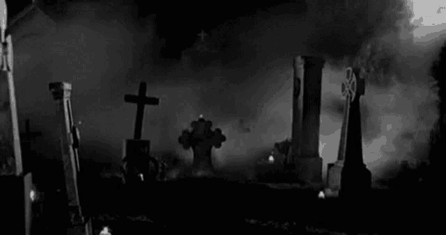 a black and white photo of a cemetery with crosses and graves covered in fog .