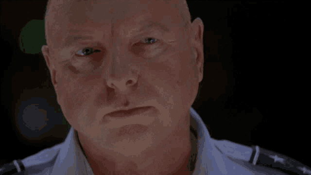 a bald man in a military uniform has a serious look on his face