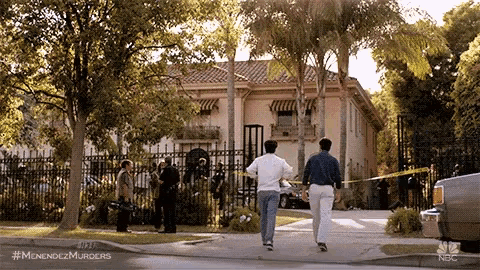 a couple of men are walking down a sidewalk in front of a large house .