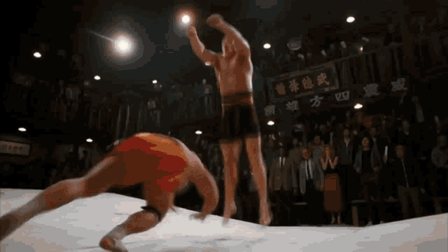 two men are fighting in a boxing ring with chinese writing on the wall