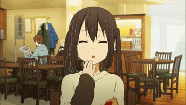 a girl with pigtails is sitting at a table in a restaurant with her eyes closed