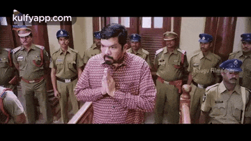 a man is praying in front of a group of police officers in a room .