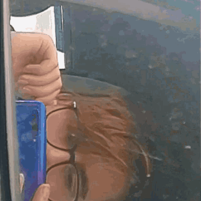 a person wearing glasses is taking a picture of their reflection in a window