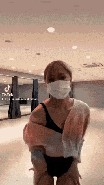 a woman wearing a face mask stands in front of a tiktok sign