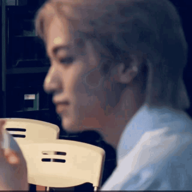 a man with blonde hair is sitting in a chair