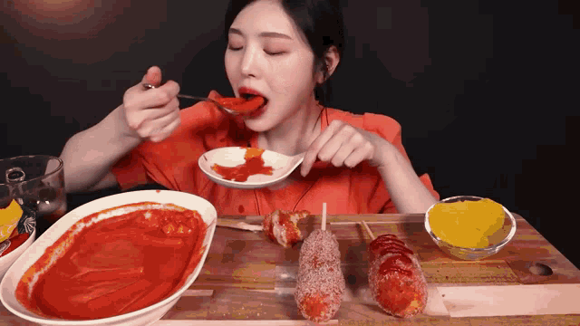 a woman is eating hot dogs with a spoon