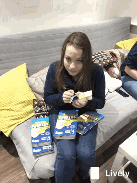 a girl is sitting on a couch with a stack of binders on her lap