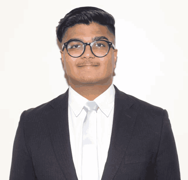 a man wearing glasses and a suit poses for a photo