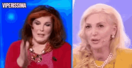 a woman in a red coat and a blonde woman in a yellow shirt are sitting next to each other on a blue background .