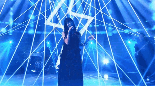 a woman singing on a stage with a drum set that says cdtv live