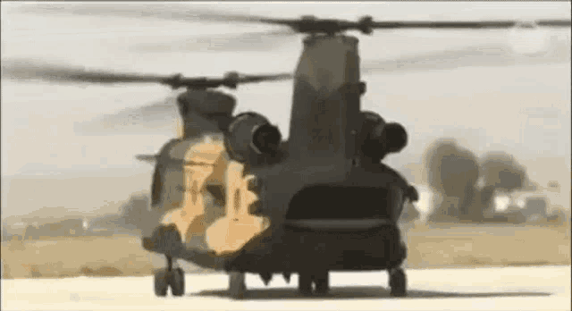 a military helicopter is sitting on top of a runway .