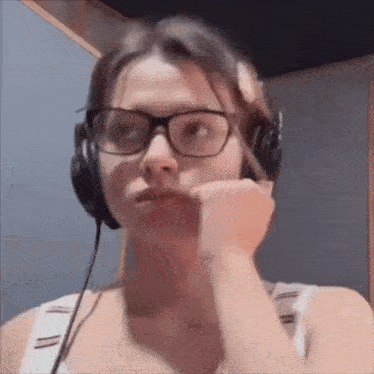 a woman wearing glasses and headphones is looking at the camera .