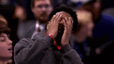 a man covering his face with his hands while watching a basketball game