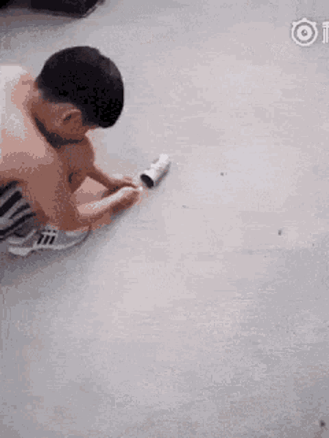 a shirtless man in striped shorts is running on a concrete floor