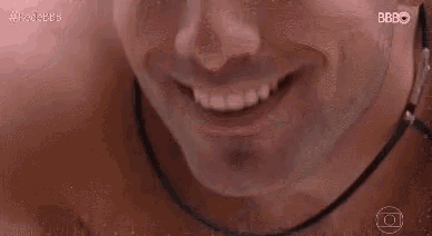a close up of a man 's face smiling with a necklace around his neck .