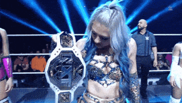 a woman with blue hair is holding a nxt belt