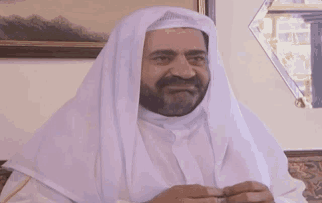 a man with a beard wearing a white shawl with arabic writing on it