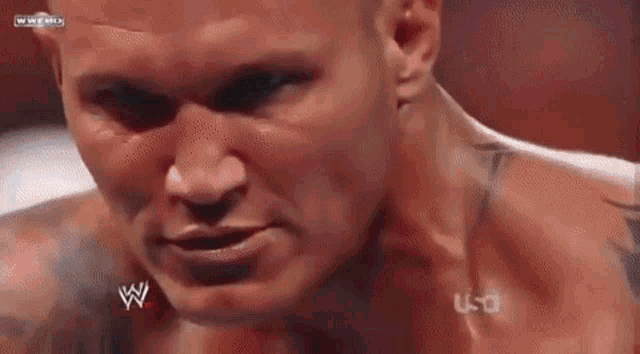 a close up of a wrestler 's face with a tattoo on his chest .