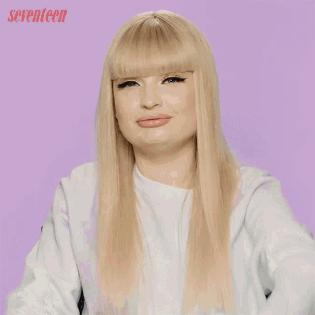 a woman with blonde hair and bangs is wearing a white shirt with seventeen written on the bottom