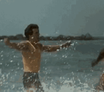 two men are playing in the water on the beach