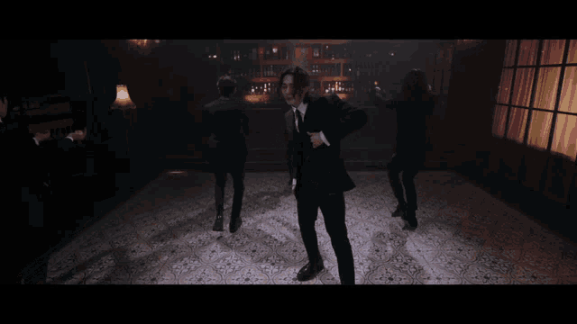 a man in a tuxedo is dancing in a dark room