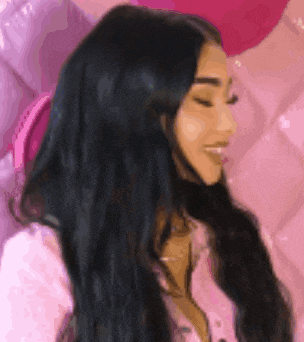 a woman with long black hair is smiling in front of a pink wall .