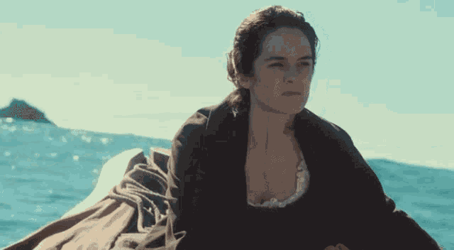 a woman is sitting on a boat in the ocean and looking at the camera .