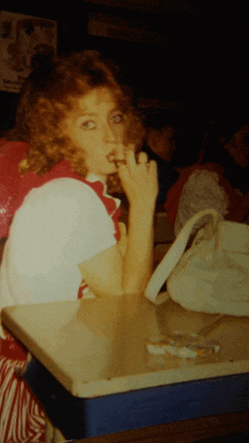 a woman sitting at a table smoking a cigarette in front of a sign that says mcdonalds