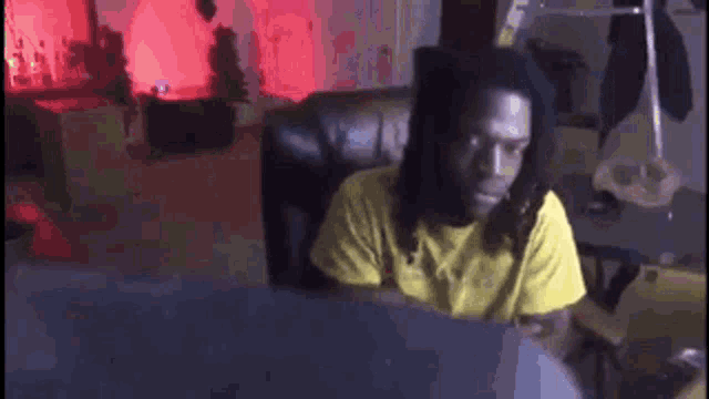 a man with dreadlocks is sitting in a chair playing drums .
