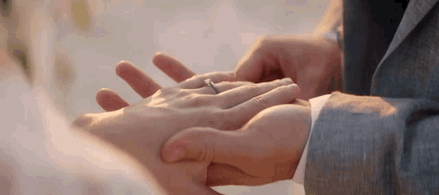 a man in a suit is putting a ring on a woman 's finger