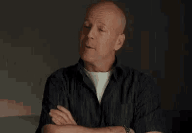 a bald man wearing a watch is smiling while looking at his watch .