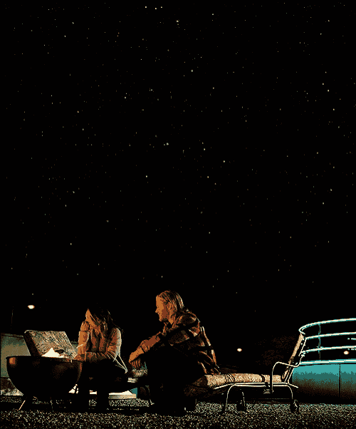 two people are sitting around a fire pit at night
